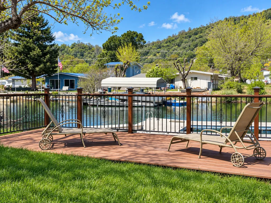 Two lounge chairs on a deck overlooking a lake with mountains in the background.