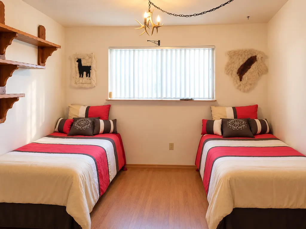 Two twin beds with red, white, and black bedding in a small bedroom.