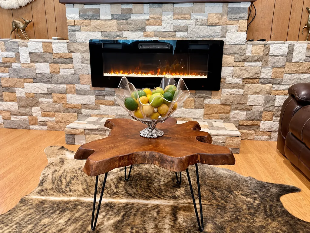 A living room with a fireplace, a wooden table with a bowl of fruit, and a brown leather chair.