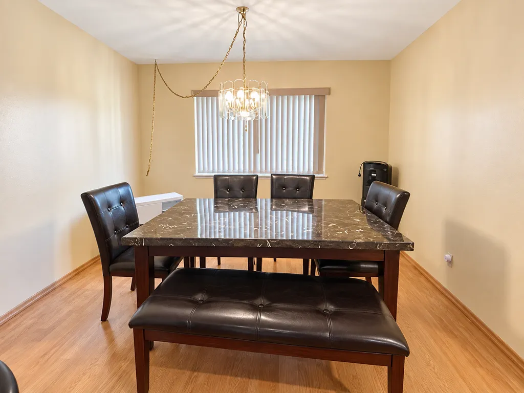Dining area with a marble table, black chairs, and a chandelier.