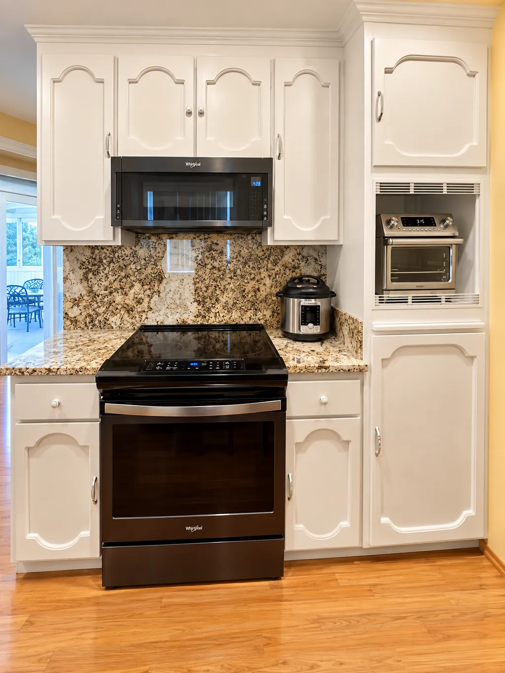 A kitchen with white cabinets, granite countertops, a black stove, and a microwave.